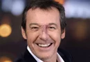 Animateur de télévision souriant en gros plan, éclairage studio, expression chaleureuse et naturelle.