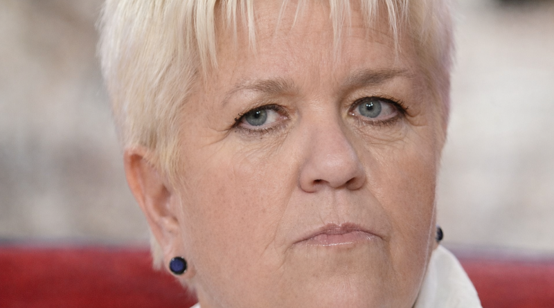 Portrait serré d’une femme aux cheveux courts clairs, assise, le regard sérieux, exprimant fatigue et introspection