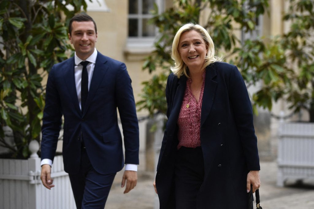 Deux responsables politiques marchant côte à côte dans une cour institutionnelle, souriants, vêtus de tenues formelles, illustrant la progression d’un courant politique dans l’opinion publique française.