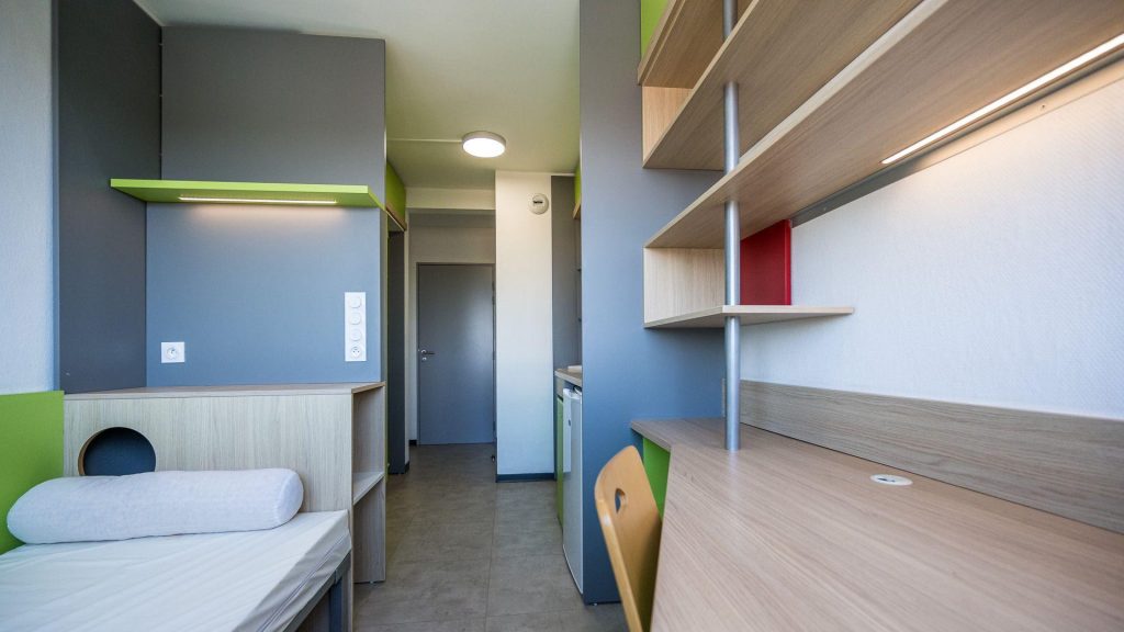 Chambre étudiante vide dans une résidence universitaire moderne, illustrant la pénurie de logements pour les étudiants.