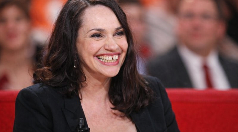 Portrait d’une actrice en interview télévisée, sourire franc, éclairage de plateau, arrière-plan flouté