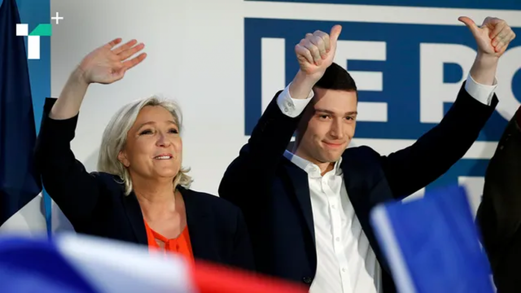 Deux responsables politiques français saluant une foule lors d’un rassemblement public, dans une ambiance de meeting avec des drapeaux tricolores