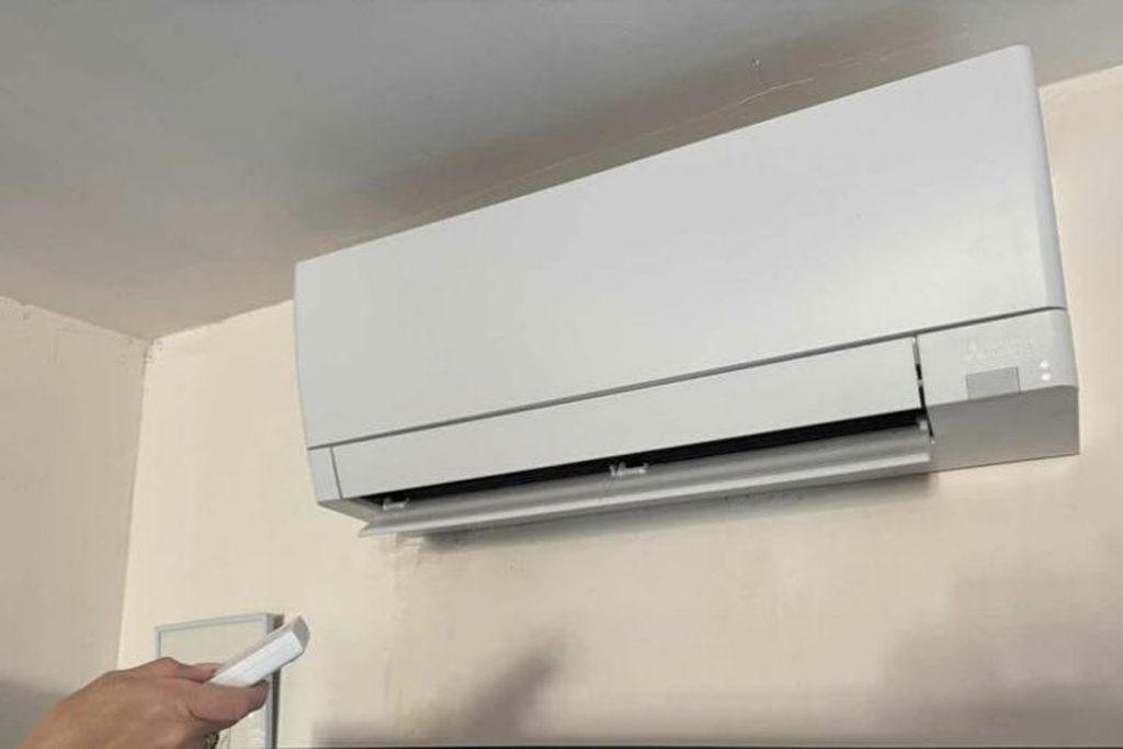 Climatisation murale installée en hauteur sur un mur clair à l’intérieur d’un logement, illustrant un système de climatisation réversible domestique.