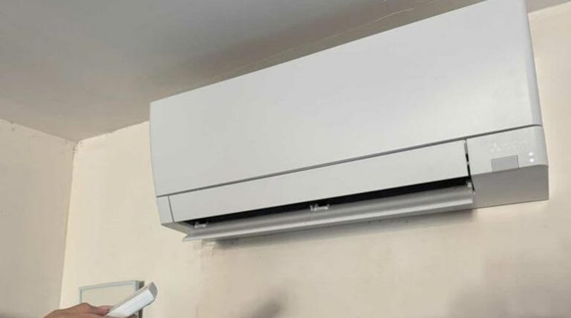 Climatisation murale installée en hauteur sur un mur clair à l’intérieur d’un logement, illustrant un système de climatisation réversible domestique.