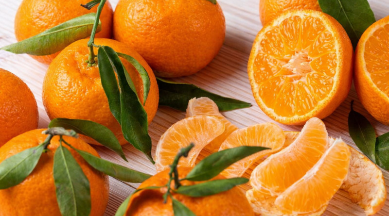 Fruits agrumes orange disposés sur une surface claire, avec plusieurs fruits entiers et des quartiers épluchés montrant une chair juteuse et brillante.