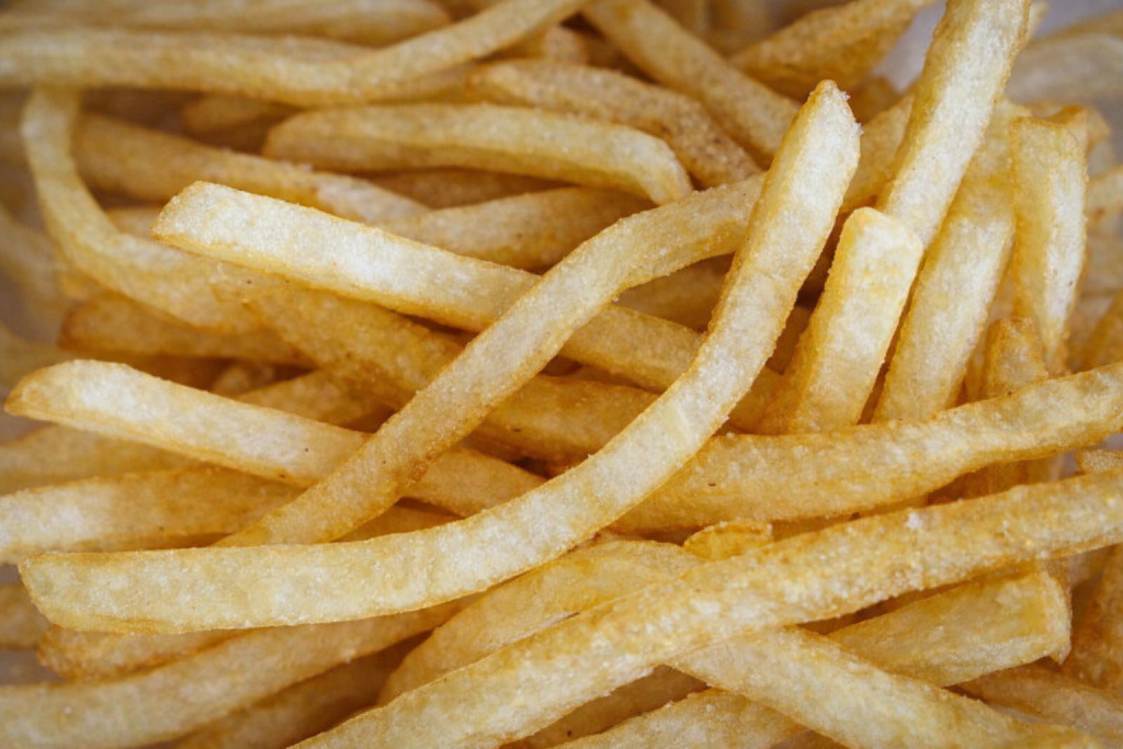 Gros plan sur des frites dorées et croustillantes empilées les unes sur les autres, prises en photo en lumière naturelle.