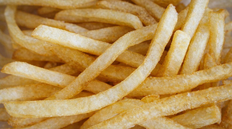 Gros plan sur des frites dorées et croustillantes empilées les unes sur les autres, prises en photo en lumière naturelle.