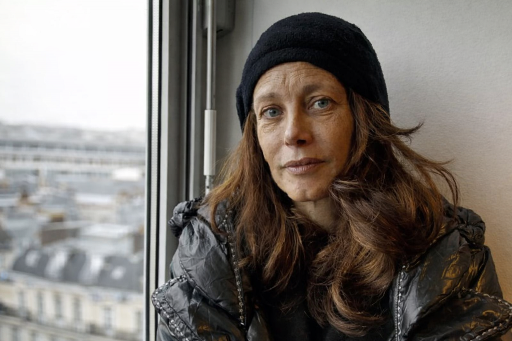 portrait d’une femme au regard marqué assise près d’une fenêtre après une période de grande précarité