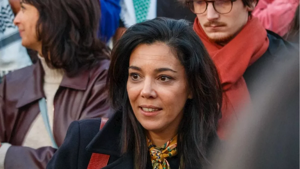 Femme engagée en politique photographiée au milieu d’un groupe de personnes lors d’un rassemblement public, regard attentif et expression concentrée.
