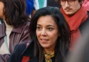 Femme engagée en politique photographiée au milieu d’un groupe de personnes lors d’un rassemblement public, regard attentif et expression concentrée.