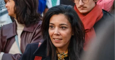 Femme engagée en politique photographiée au milieu d’un groupe de personnes lors d’un rassemblement public, regard attentif et expression concentrée.