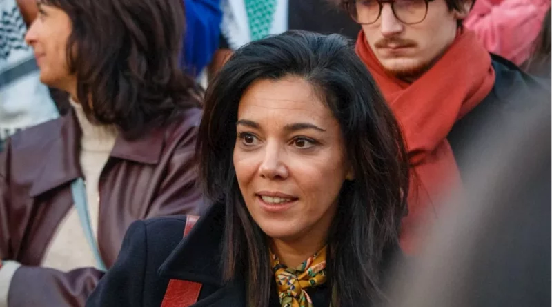 Femme engagée en politique photographiée au milieu d’un groupe de personnes lors d’un rassemblement public, regard attentif et expression concentrée.