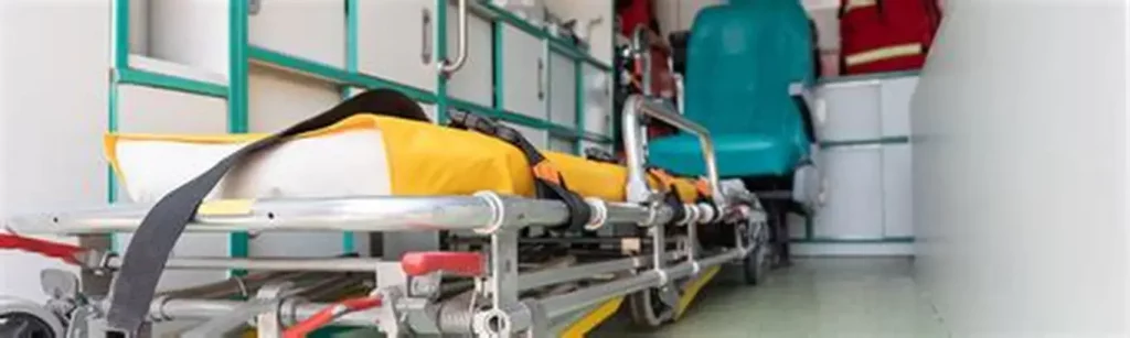 Brancard médical vide à l’intérieur d’une ambulance, sangles de maintien visibles, matériel de secours rangé autour, atmosphère d’urgence et de tension médicale.