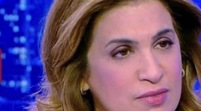 Journaliste femme en plateau de télévision, expression sérieuse et concentrée, éclairage bleu d’un studio d’actualité, ambiance tendue, cadrage serré sur le visage