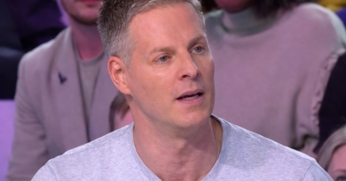 Chroniqueur de télévision assis sur un plateau, parlant face au public, éclairage de studio et ambiance de débat médiatique