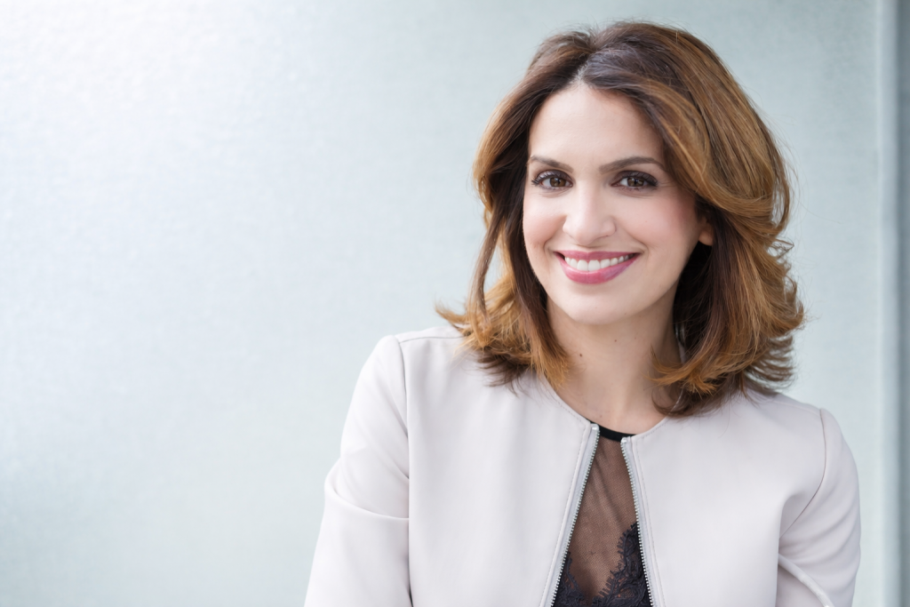 Portrait d’une journaliste souriante, éclairage naturel, tenue claire, fond uni et lumineux