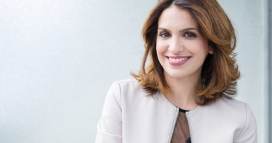 Portrait d’une journaliste souriante, éclairage naturel, tenue claire, fond uni et lumineux