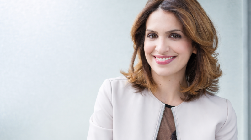 Portrait d’une journaliste souriante, éclairage naturel, tenue claire, fond uni et lumineux