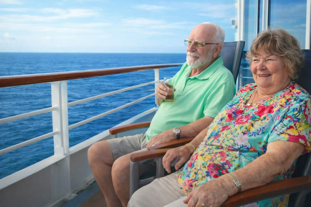 Couple de personnes âgées assises sur le pont d’un navire de croisière, face à la mer, profitant d’un moment de détente dans un cadre calme et lumineux.