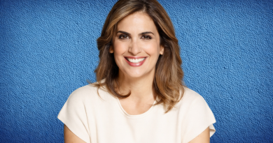 Portrait d’une présentatrice de télévision souriante, cadrée en buste, devant un fond bleu uni