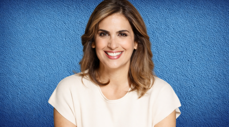 Portrait d’une présentatrice de télévision souriante, cadrée en buste, devant un fond bleu uni