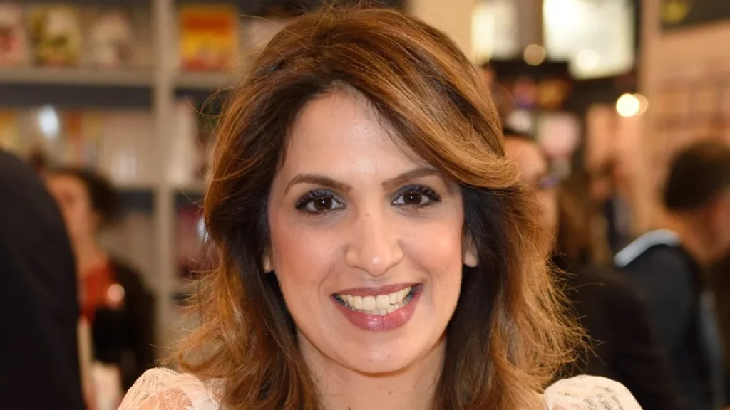 Portrait rapproché d’une présentatrice de télévision souriante lors d’un événement public en intérieur