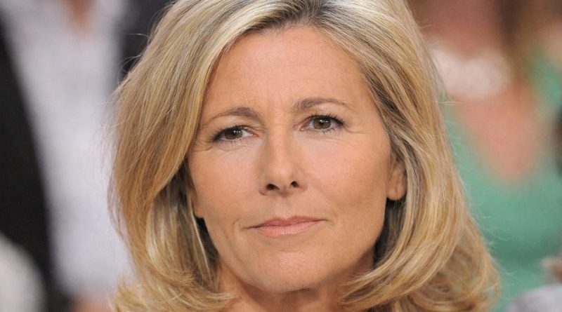 portrait en gros plan d’une présentatrice de télévision blonde au regard sérieux lors d’une émission, visage éclairé par une lumière de studio avec un public flou en arrière-plan
