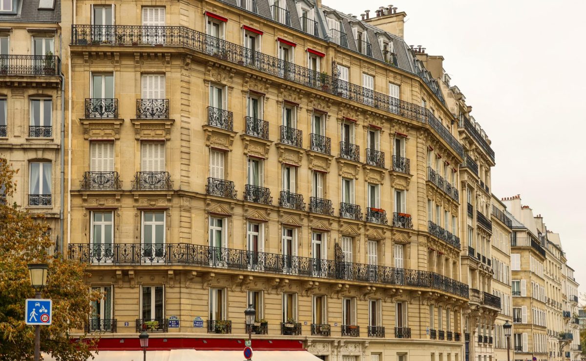 immeuble haussmannien typique avec façade en pierre, balcons en fer forgé et rangées de fenêtres dans une rue urbaine calme