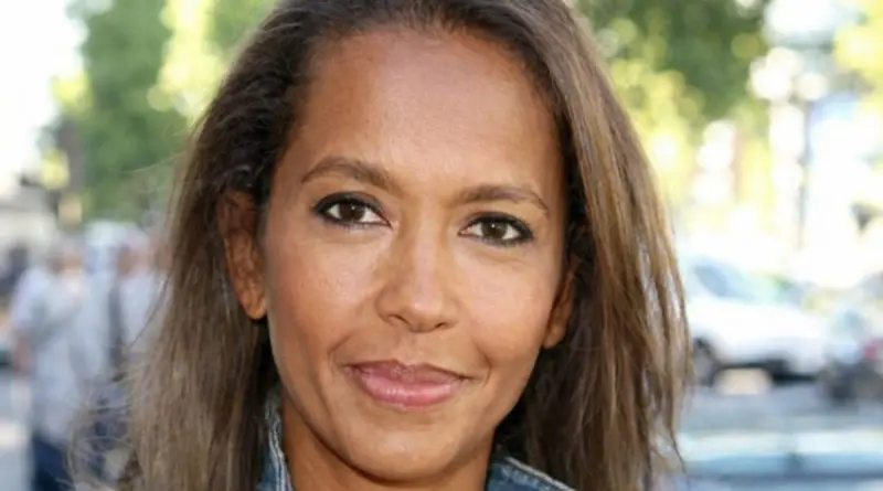 portrait d’une animatrice française en extérieur regardant directement la caméra avec une expression douce et engagée, lumière naturelle et arrière-plan flou urbain