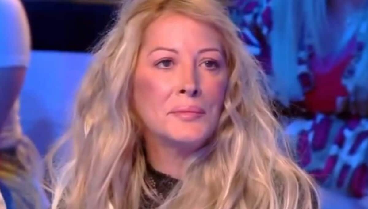 Femme blonde au regard triste sur un plateau de télévision, visage marqué par la fatigue et l’émotion, illustrant la descente aux enfers d’une ancienne célébrité de la télé-réalité