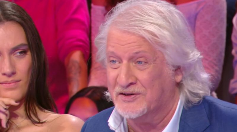 animateur français aux cheveux blancs s’exprimant sur un plateau de télévision devant un public lors d’une émission de débat