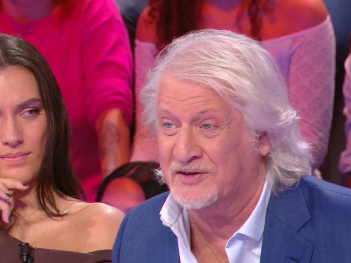 animateur français aux cheveux blancs s’exprimant sur un plateau de télévision devant un public lors d’une émission de débat