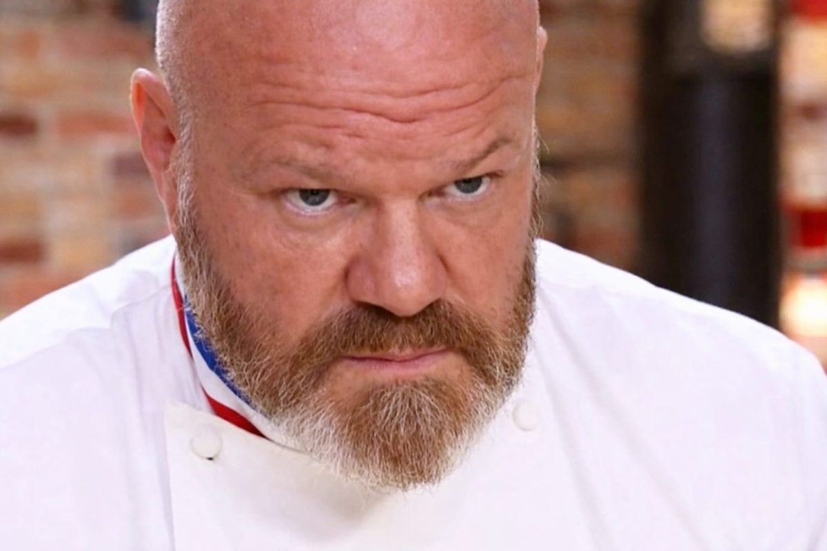 chef cuisinier en veste blanche regard sévère dans une cuisine de restaurant pendant un moment de tension en plein service