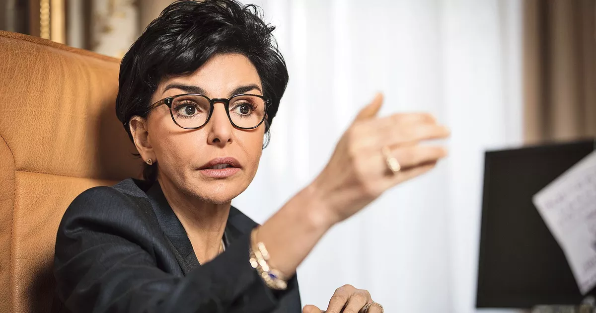 Femme politique en train de parler avec un geste de la main, regard intense et expression sérieuse dans un bureau officiel