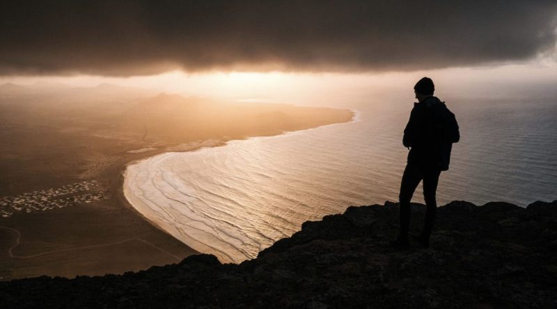 Personne assise seule face à l’horizon au lever du soleil, symbole de reconstruction personnelle et de nouveau départ après des années de souffrance et d’addictions.