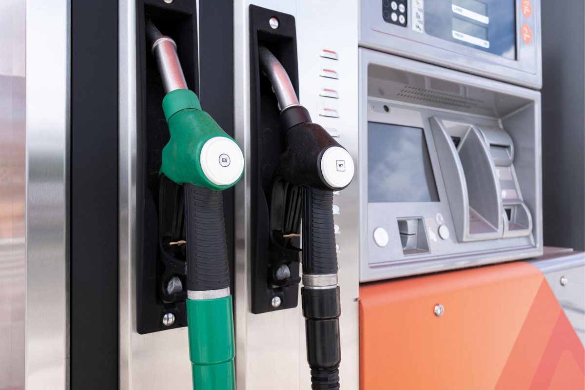 Pompes de carburant dans une station-service avec deux pistolets de distribution, l’un vert et l’autre noir, insérés dans leurs supports sur une borne de pompe moderne, illustrant le ravitaillement en essence ou en diesel par les automobilistes.