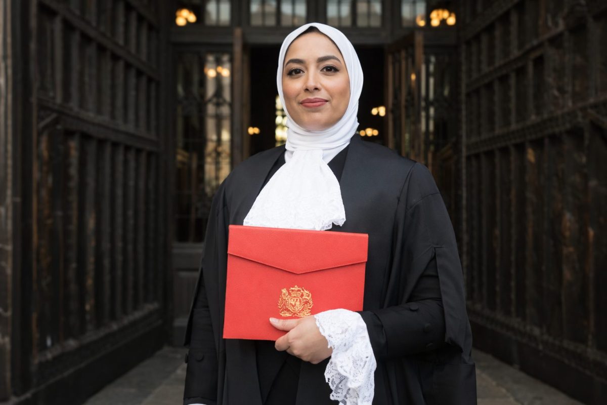 Avocate portant une robe noire et un voile blanc devant l’entrée d’un tribunal, tenant un dossier rouge, illustrant le débat sur le port de signes religieux et la neutralité dans la justice en France.