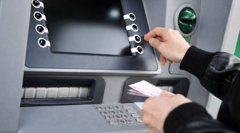 main d’un homme retirant de l’argent à un distributeur automatique avec une carte bancaire, écran flouté, ambiance neutre illustrant un retrait suspect et une possible fraude bancaire