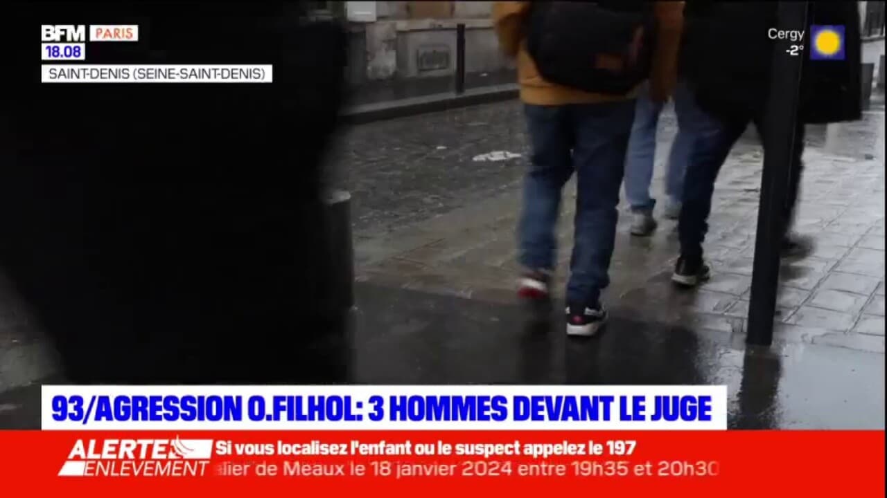 scène filmée dans une rue de Saint-Denis sous la pluie, plusieurs personnes marchent sur un trottoir humide, ambiance urbaine tendue avec présence d’une équipe de reportage en arrière-plan lors d’une intervention médiatique