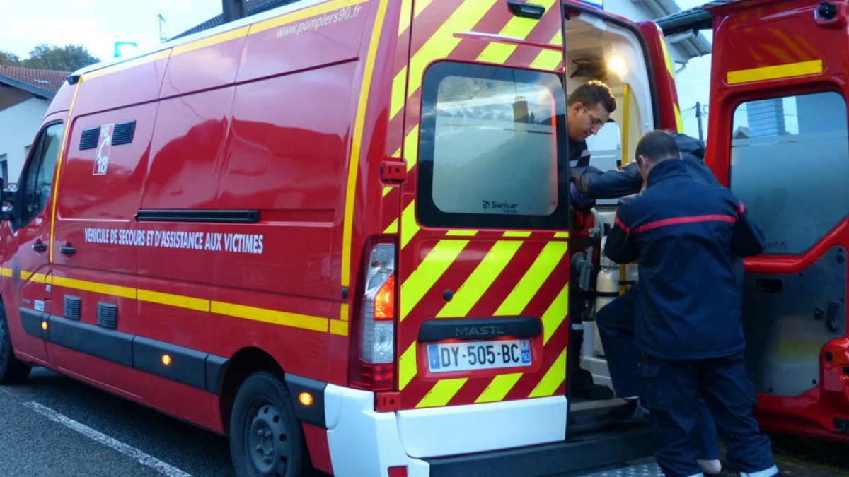 Intervention des secours devant une maison dans un quartier résidentiel, deux secouristes prennent en charge une victime à l’arrière d’un véhicule d’assistance, ambiance d’urgence après une altercation violente