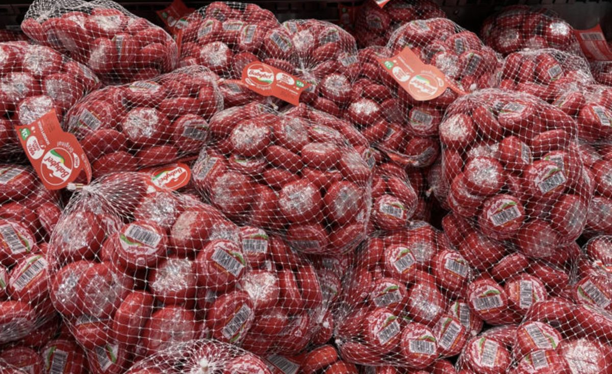 Filets remplis de petites portions de fromage rondes recouvertes de cire rouge, empilées en grande quantité dans un rayon de supermarché