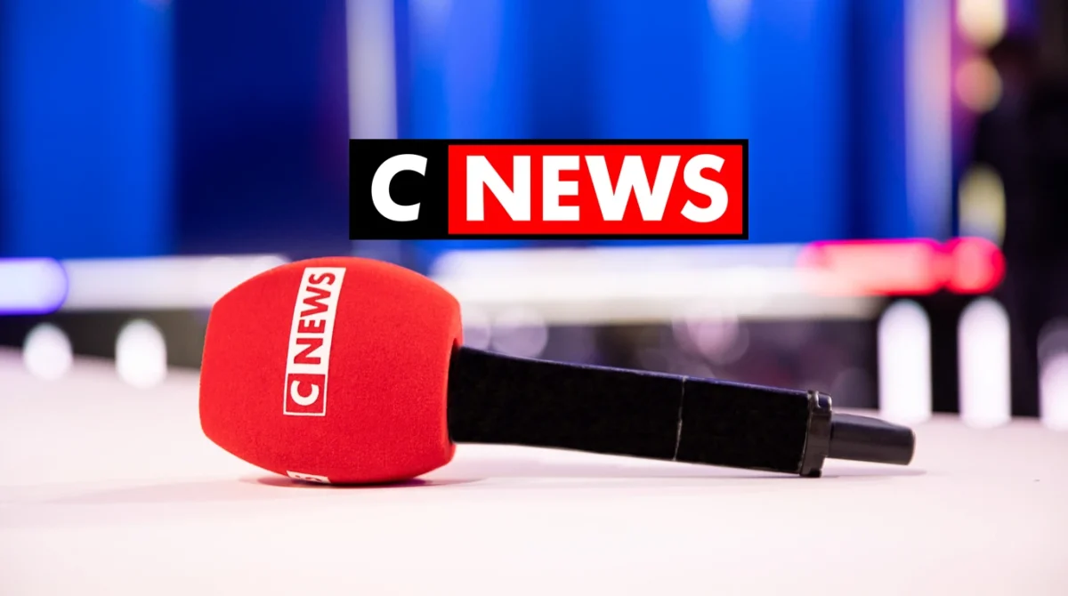 micro rouge de chaîne d’information posé sur une table en studio télé, fond flou bleu et ambiance plateau, illustration d’une polémique médiatique et d’un débat sur les médias en France
