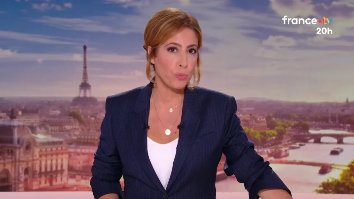Présentatrice de journal télévisé en studio face caméra, regard sérieux et posture professionnelle, avec une grande ville en arrière-plan légèrement floutée, ambiance de JT national évoquant une forte exposition médiatique et une polémique autour de sa rémunération