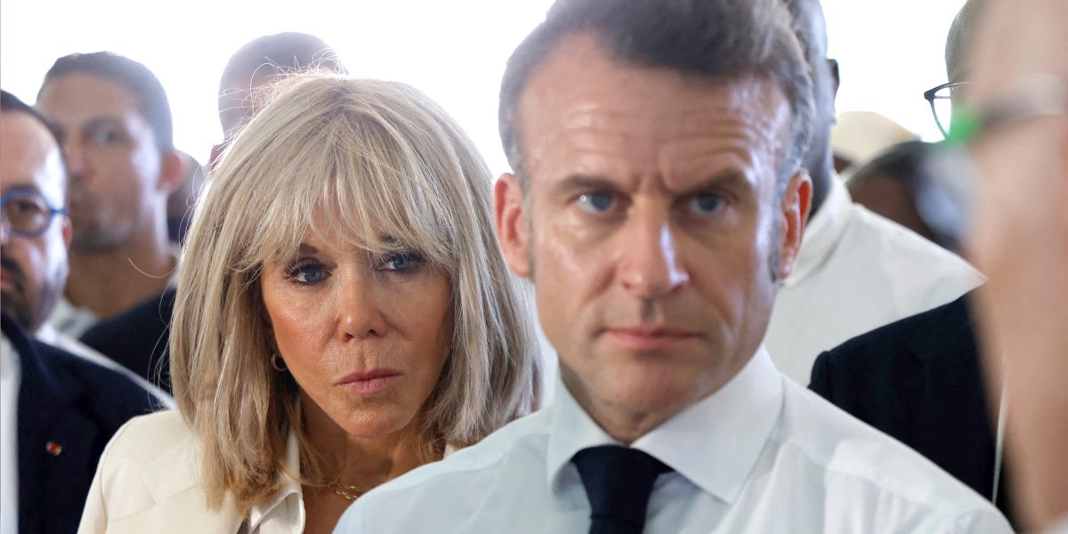 Couple présidentiel français au milieu d’une foule, visages sérieux et regard tendu, ambiance de tension politique et médiatique autour d’une affaire polémique