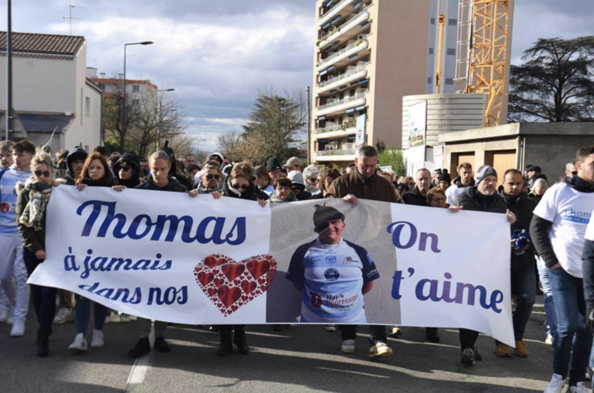 Marche blanche en hommage à un jeune homme assassiné, avec un groupe de personnes avançant dans la rue derrière une banderole, ambiance solennelle et recueillement collectif