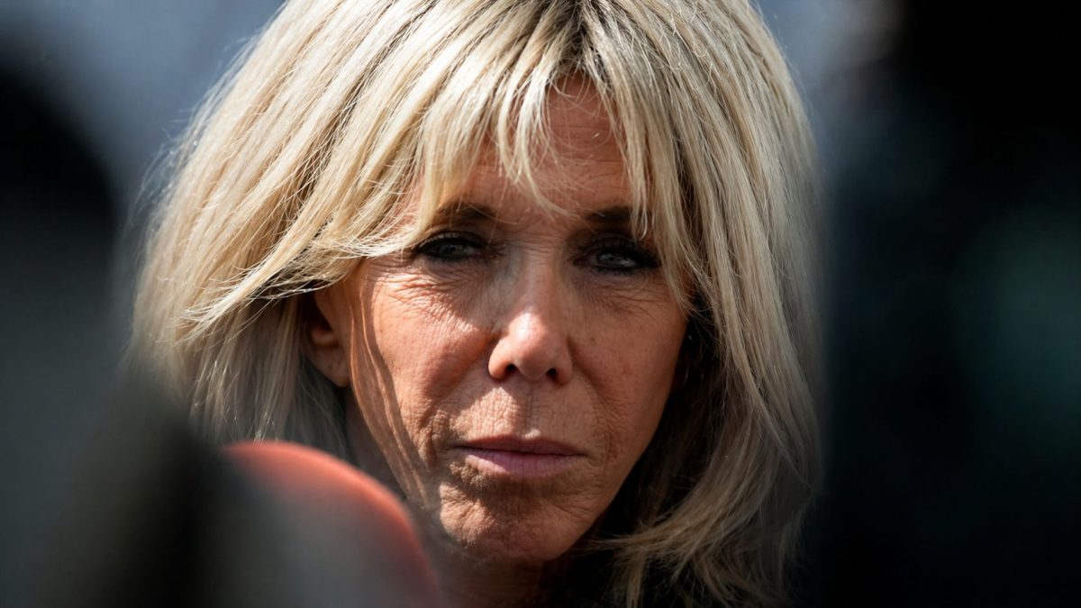 Gros plan sur une femme blonde au regard intense et marqué, visage sérieux, capturée en extérieur avec un arrière-plan flou