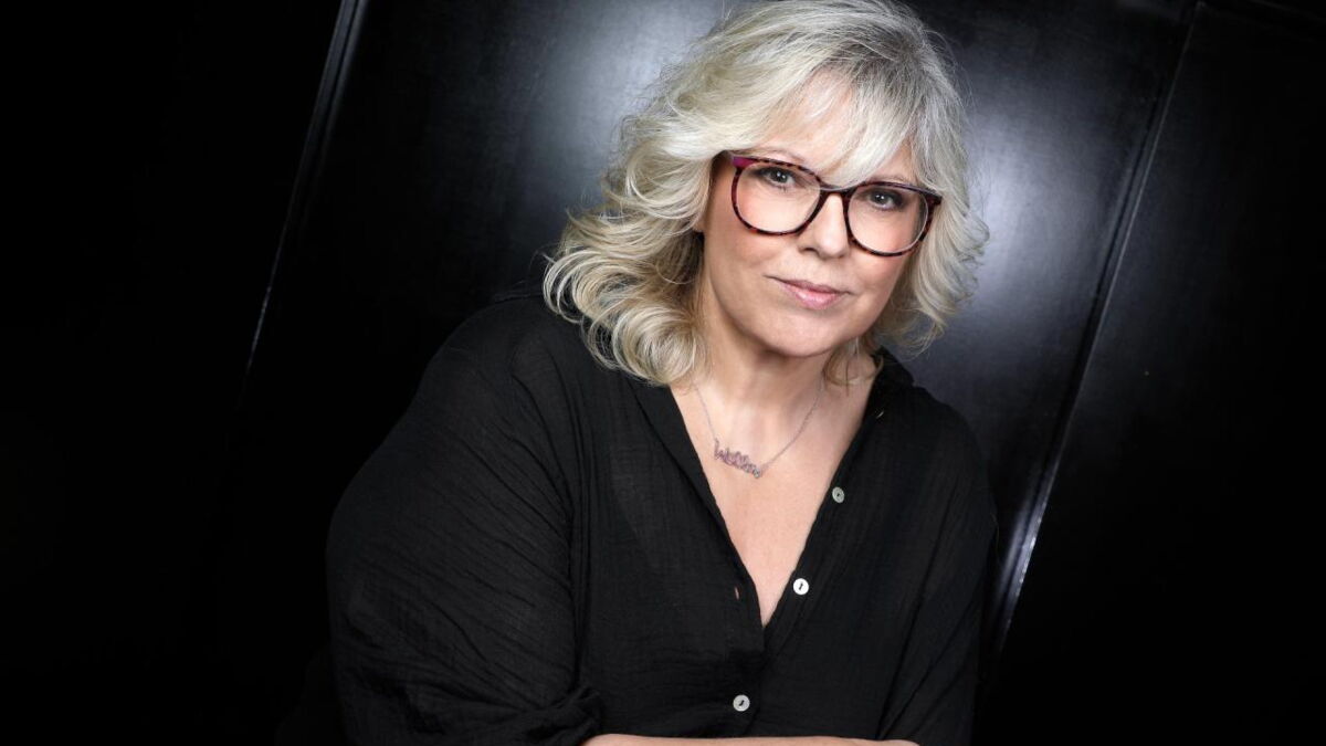 Femme blonde portant des lunettes avec une expression sérieuse, assise sur fond sombre, illustrant un témoignage sur une relation toxique et des violences psychologiques