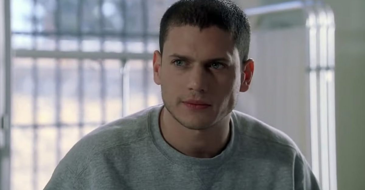 Homme au regard intense avec tête rasée, expression concentrée, dans une scène dramatique en intérieur avec éclairage sombre et ambiance tendue.