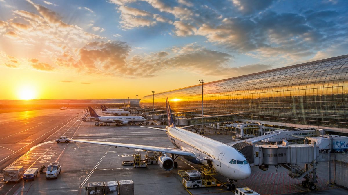 Vue panoramique d’un aéroport international avec plusieurs avions stationnés au sol près des terminaux, illustrant le contexte d’un tournage télé controversé et une affaire de discrimination présumée envers des salariés noirs à Roissy