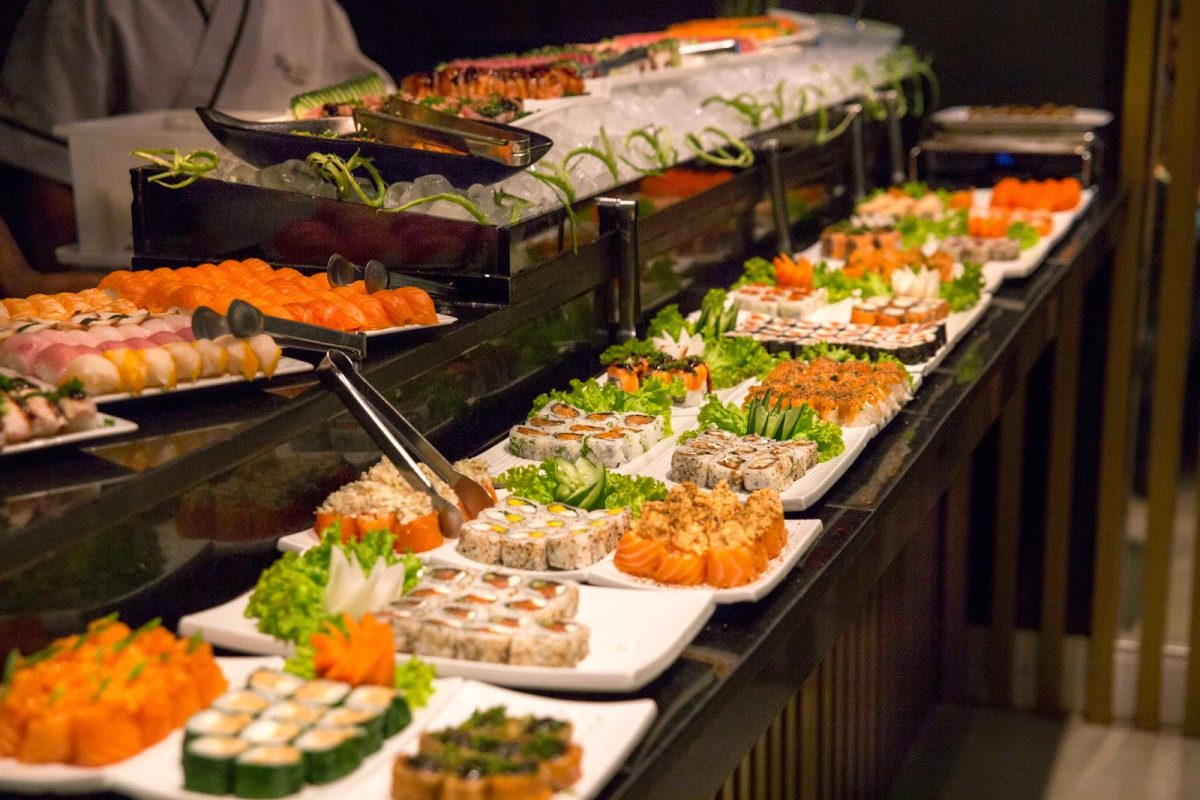 Buffet asiatique à volonté avec de nombreux plateaux de sushis, makis et spécialités japonaises disposés en libre-service dans un restaurant élégant, illustration des nouvelles règles contre le gaspillage alimentaire dans les buffets à volonté.